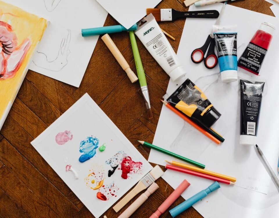 A vibrant flatlay of various art supplies on a wooden table, ideal for creative projects.