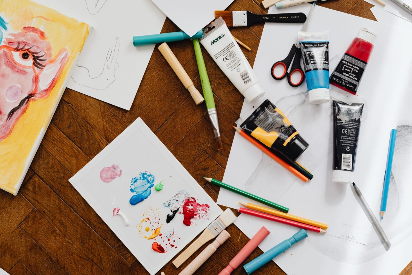A vibrant flatlay of various art supplies on a wooden table, ideal for creative projects.