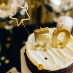 Elegant cake with golden 50th birthday topper and star decorations.