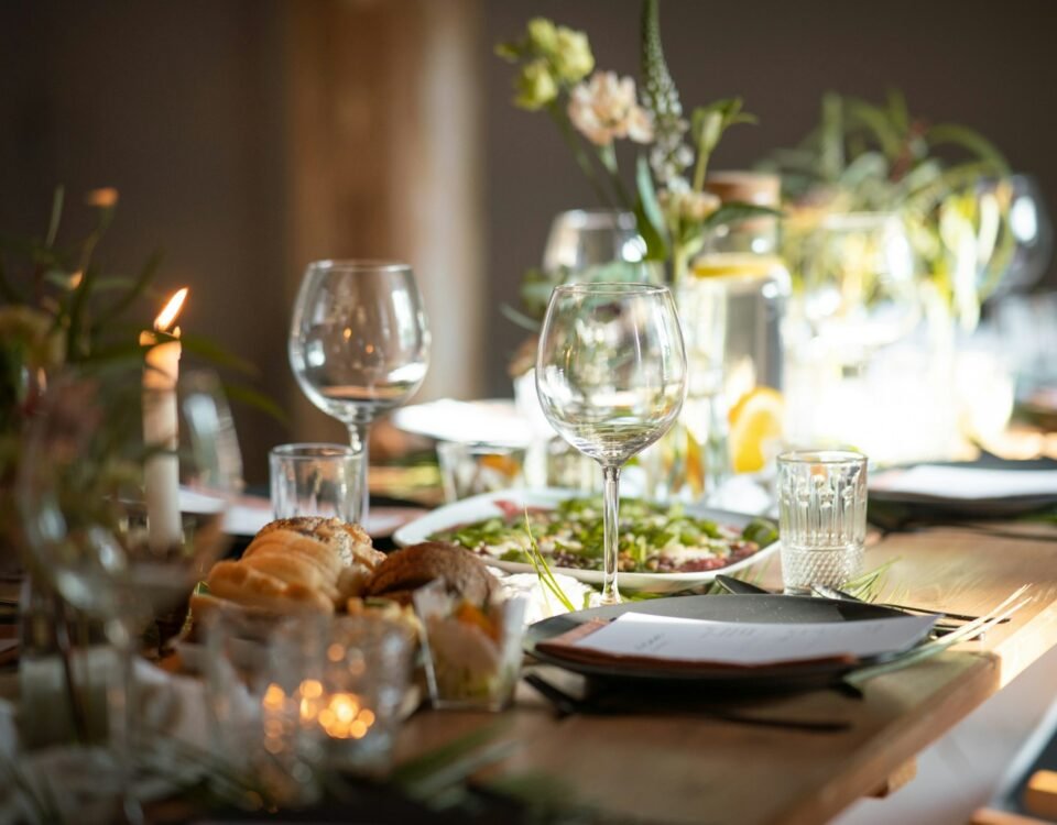 a table set for a formal dinner with wine glasses and plates